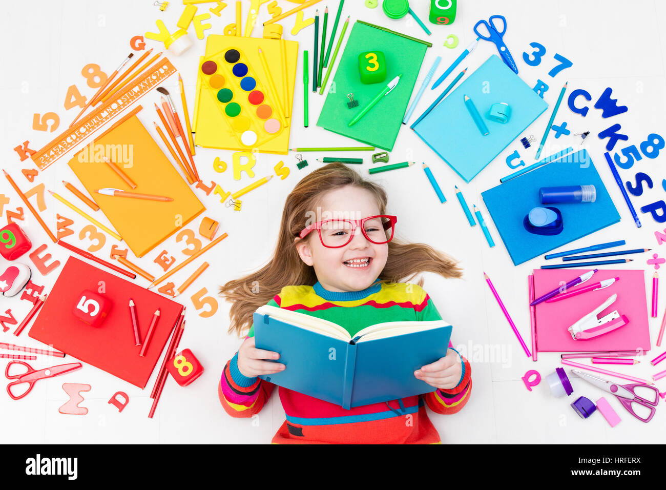 Little girl with school supplies, books, drawing and painting tools and