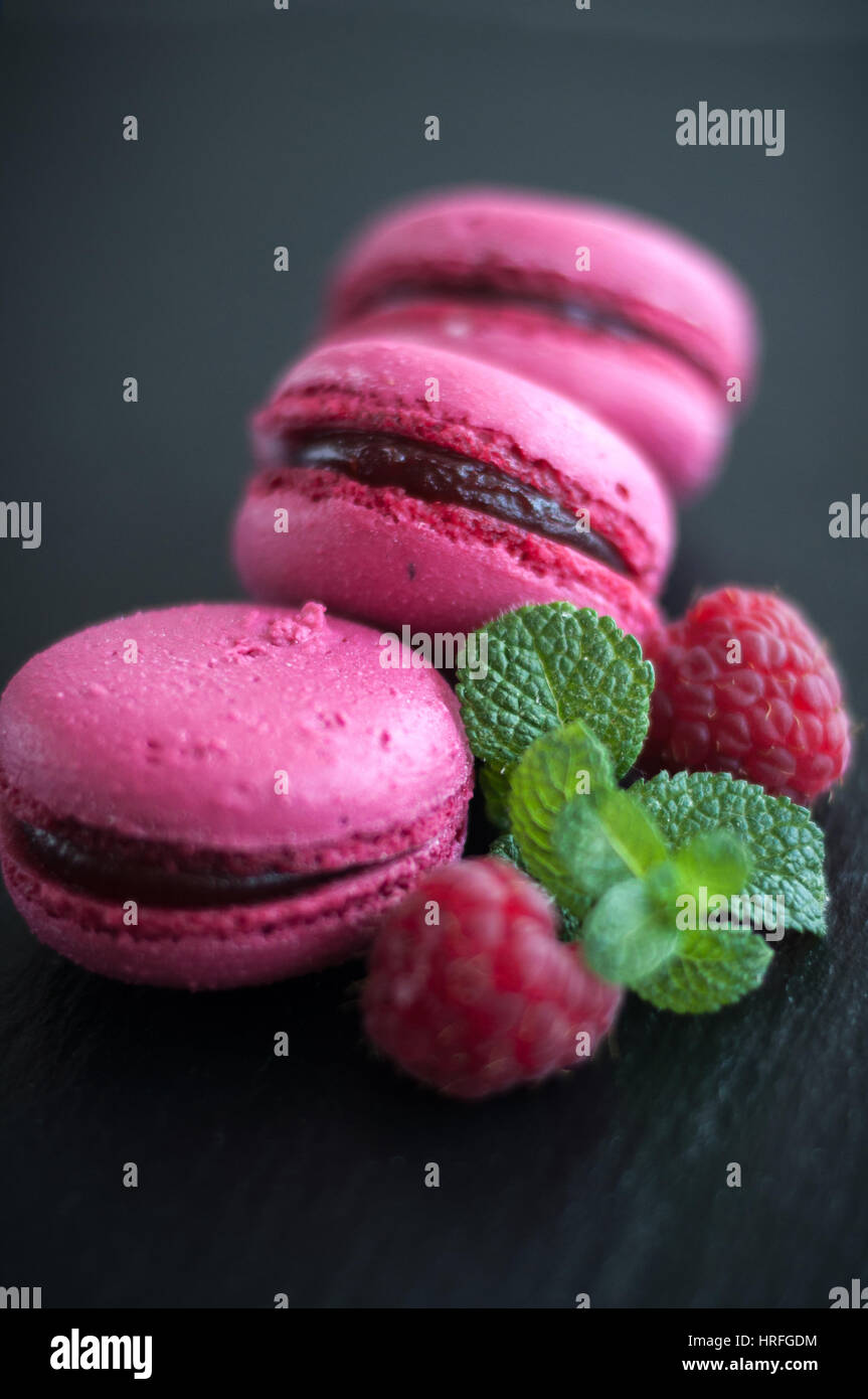 pink macaroons with raspberries on black background Stock Photo - Alamy