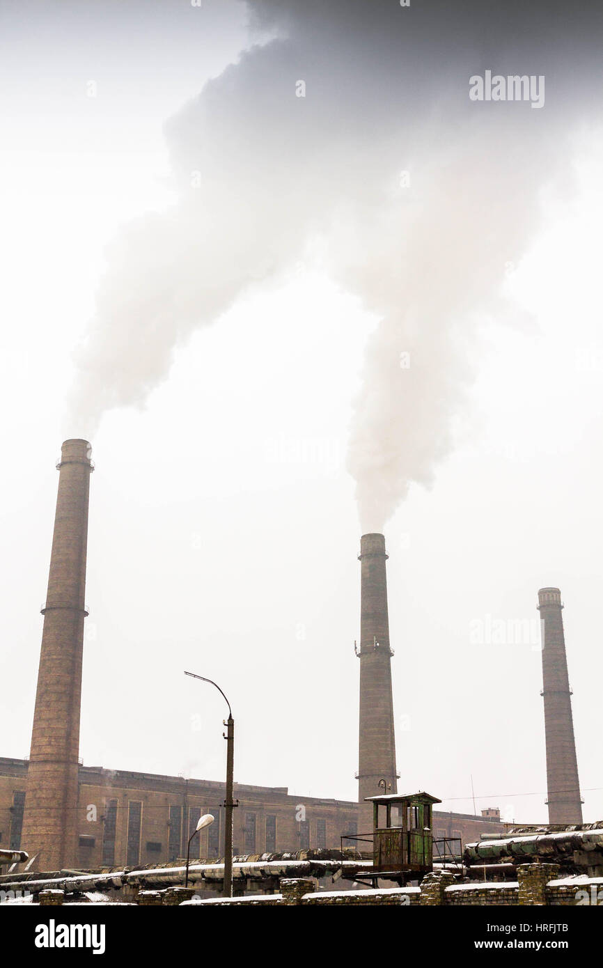 Grey smoke coming from the factory. Smoking industrial pipes. Stock Photo