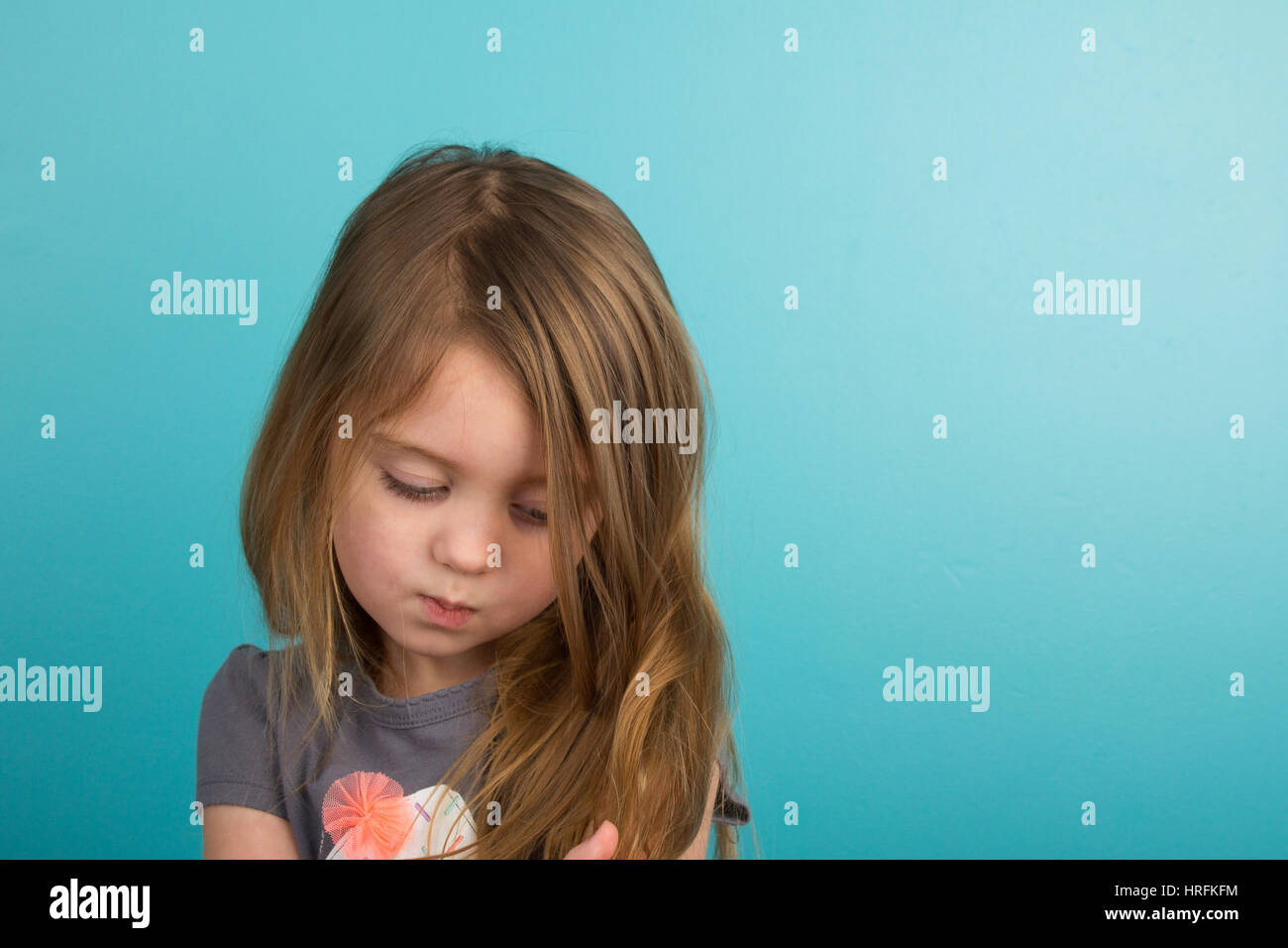 Sad little girl against teal background Stock Photo
