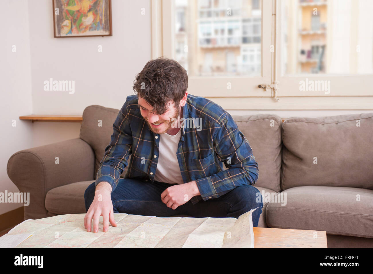 Young man at his living room with a plaid shirt and a map Stock Photo