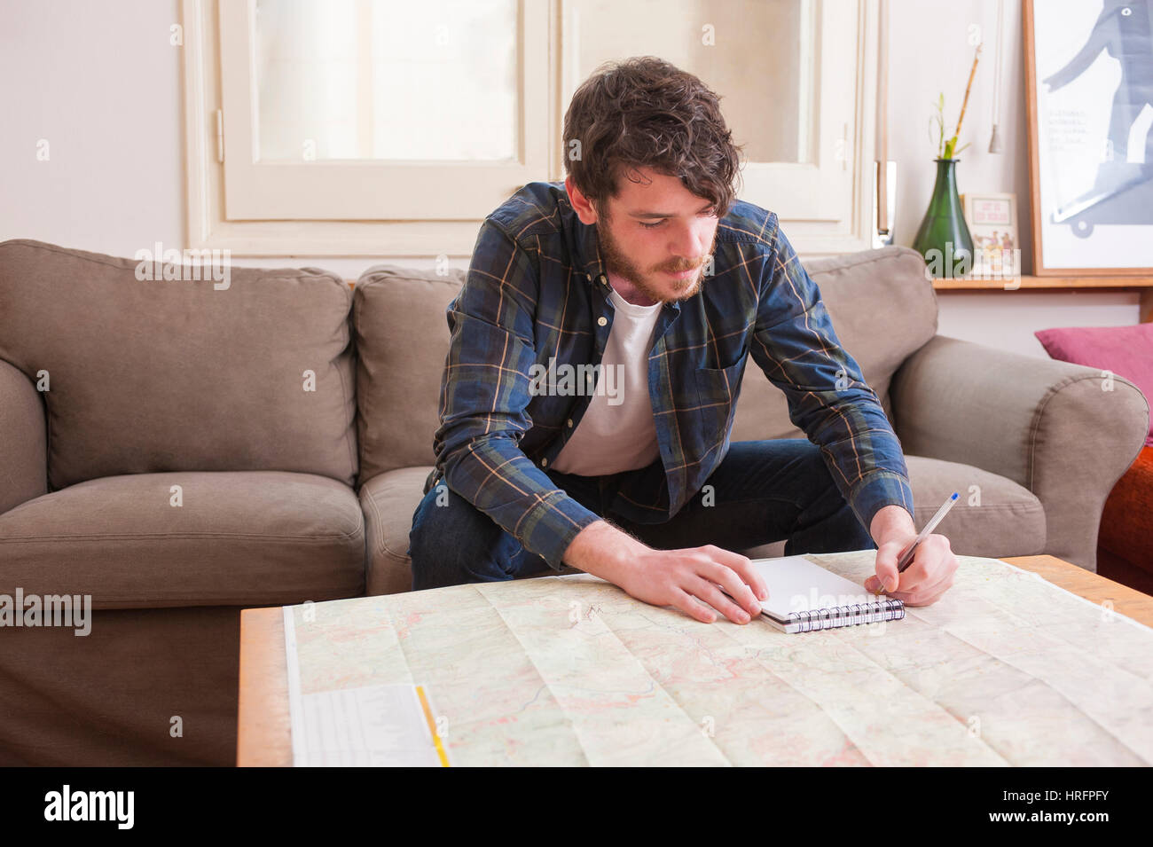 Young man at his living room with a plaid shirt and a map Stock Photo