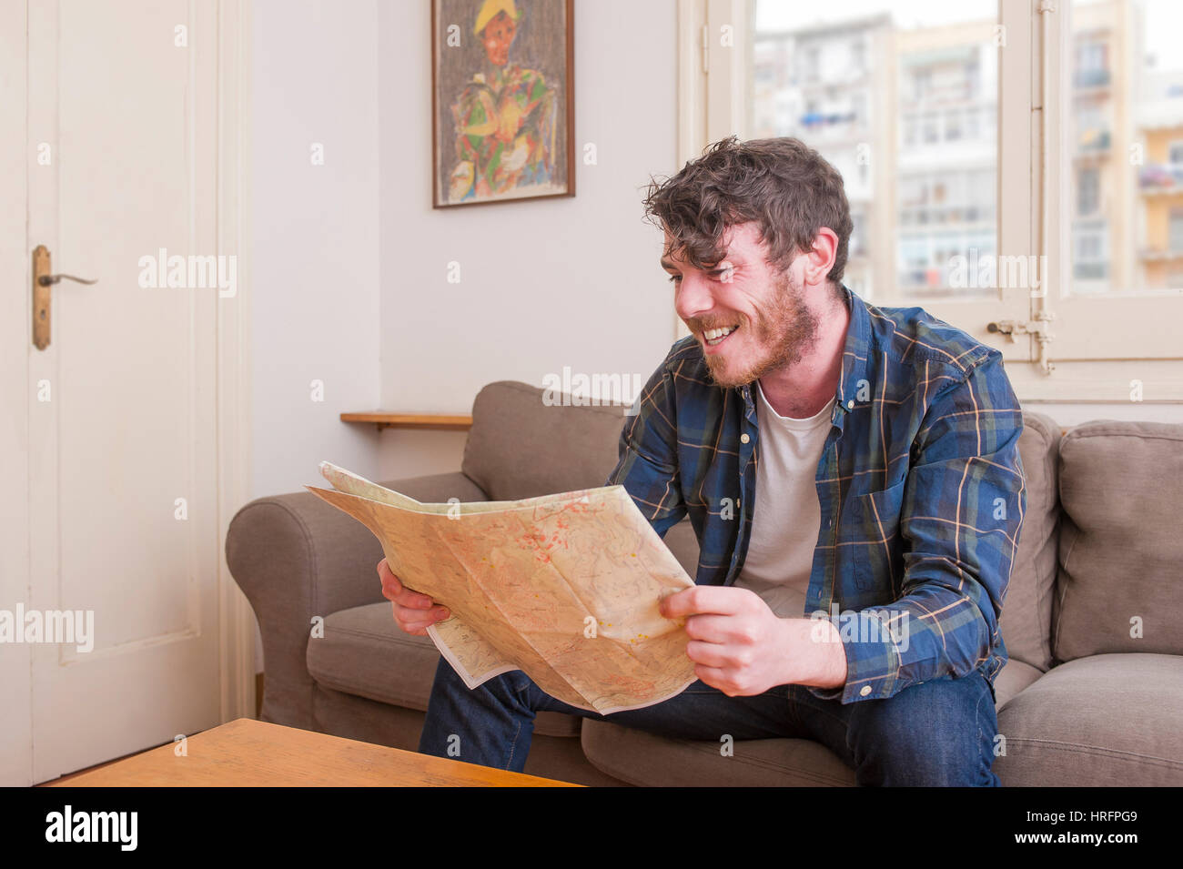Young man at his living room with a plaid shirt and a map Stock Photo