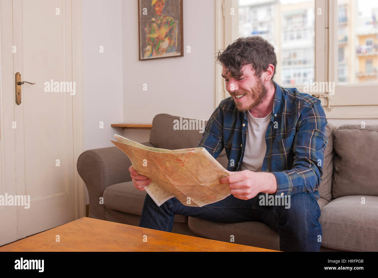 Young man at his living room with a plaid shirt and a map Stock Photo