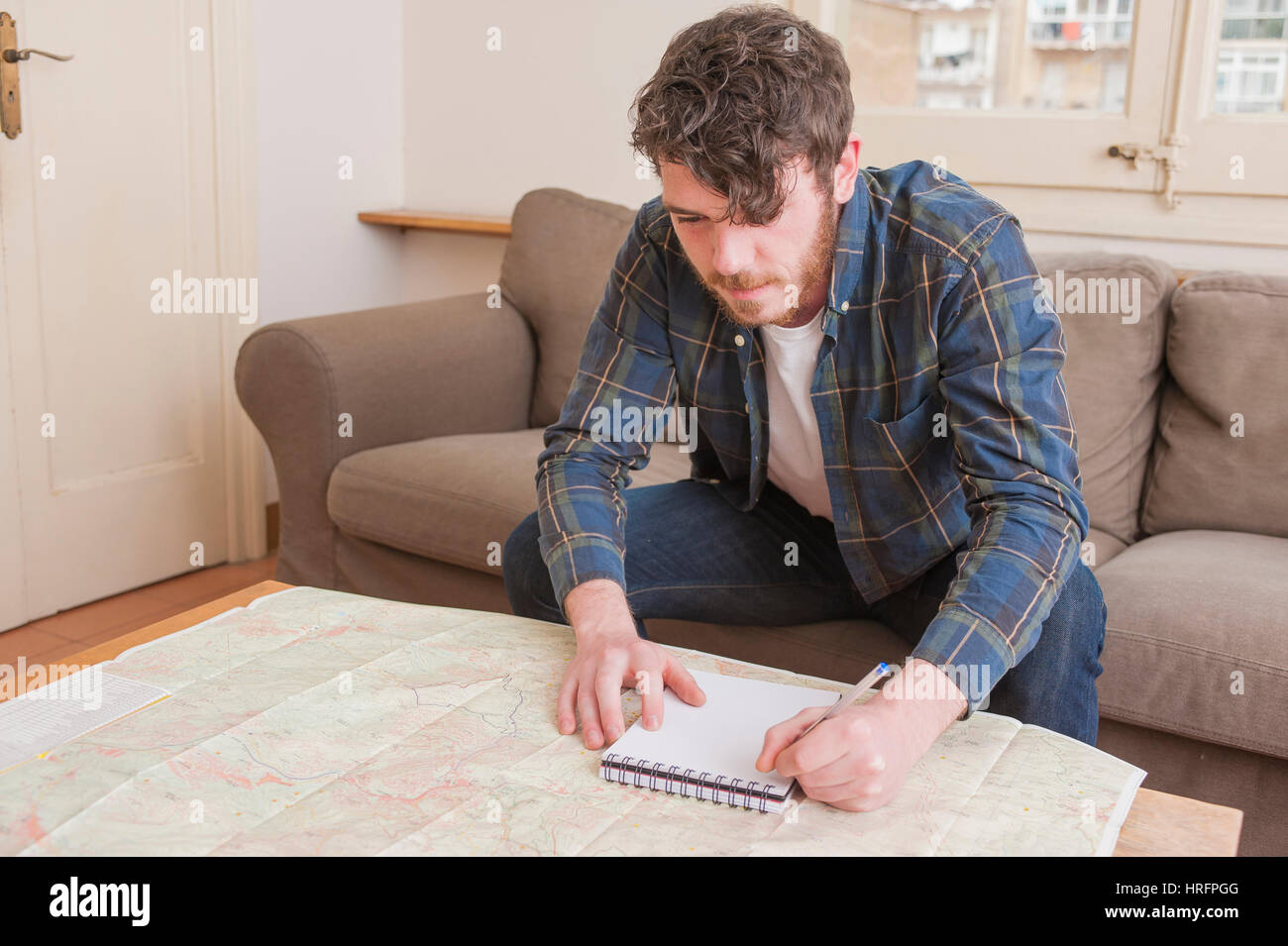 Young man at his living room with a plaid shirt and a map Stock Photo