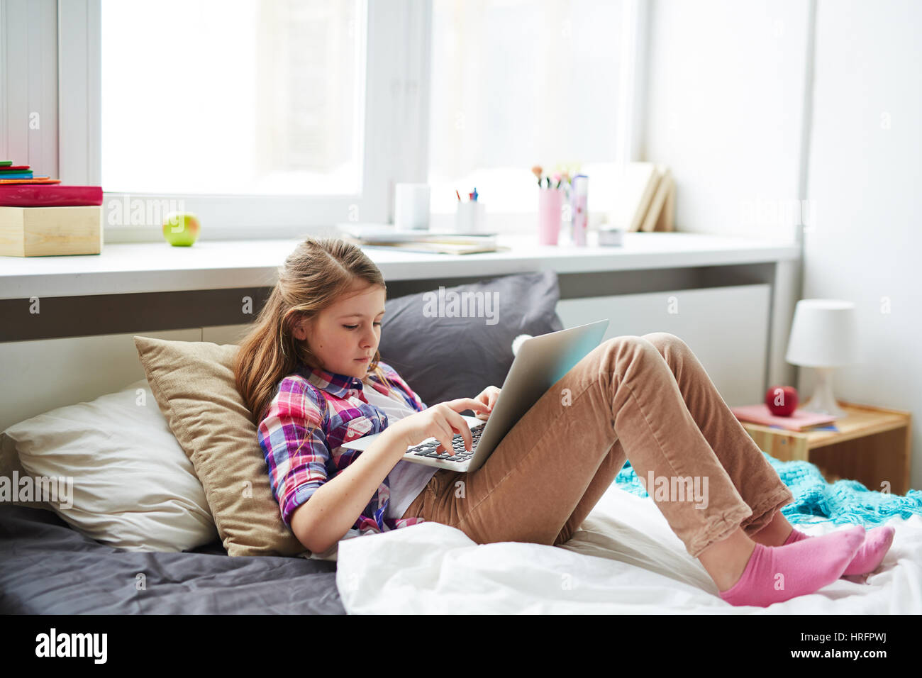Teenage girl sitting alone in cozy bedroom and playing games on her laptop Stock Photo Alamy