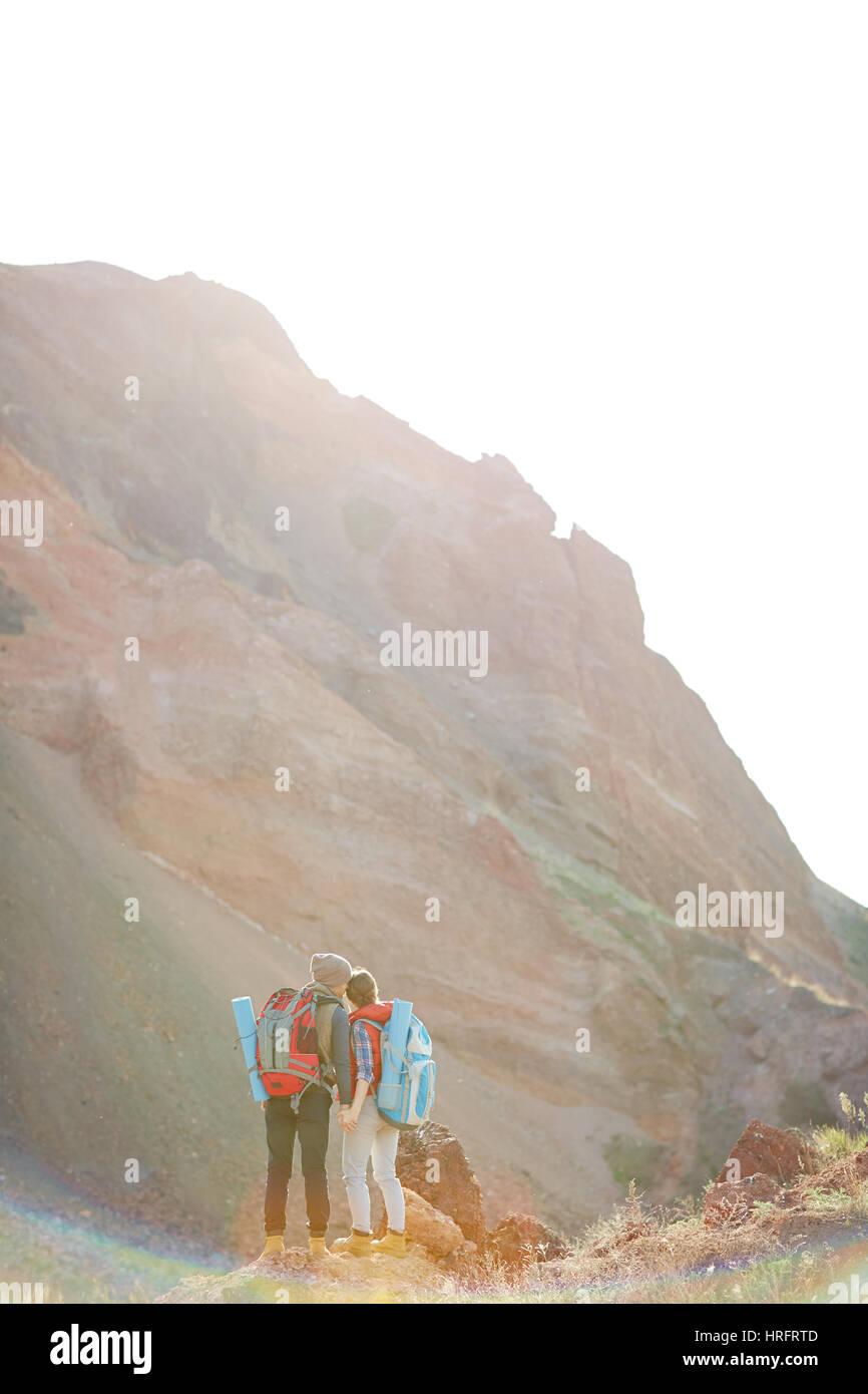 Rear view of tourist couple with big backpacks holding hands at hike in ...