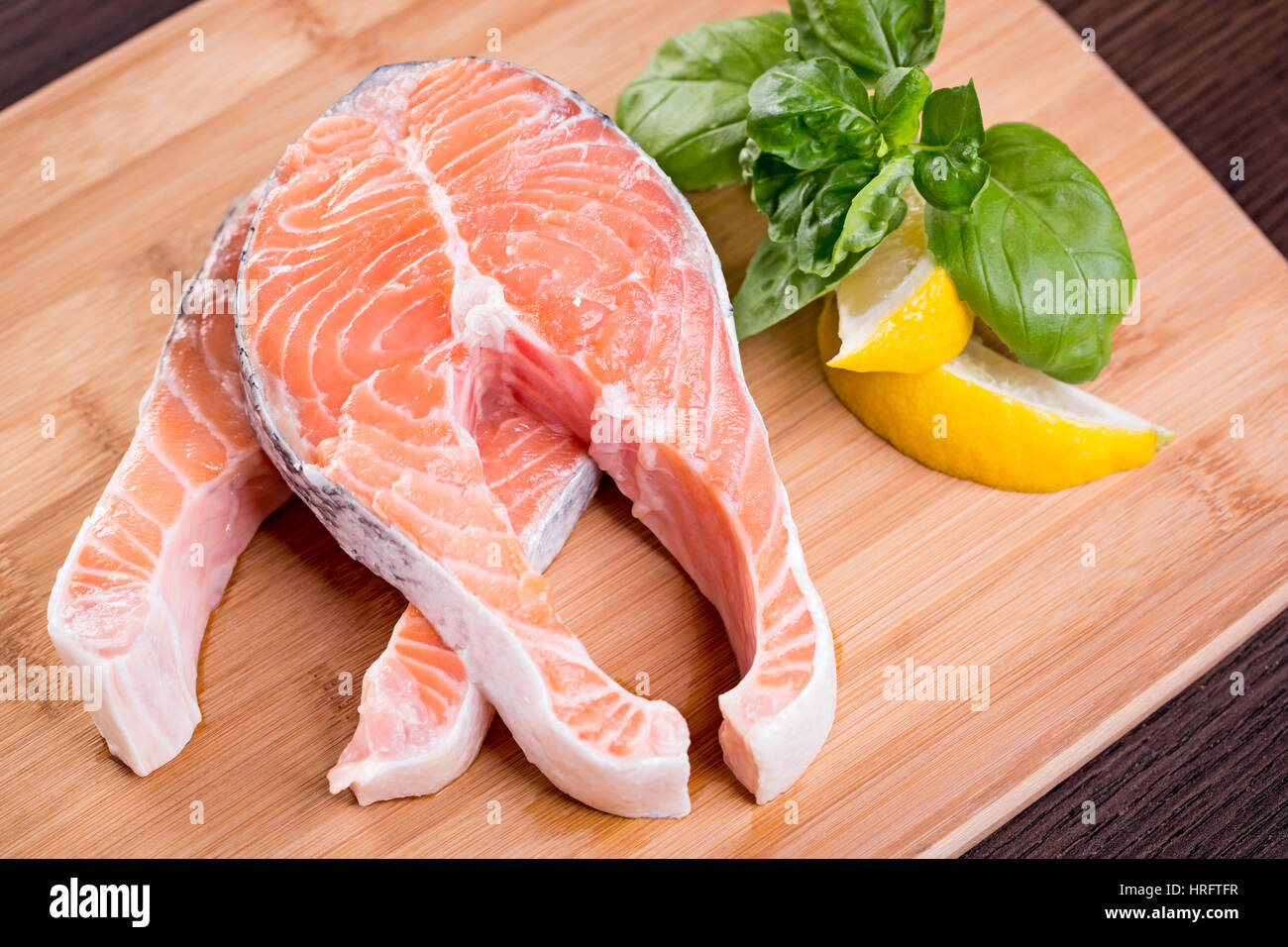 Raw fish fillet with lemon and basil on wooden cutting board Stock Photo -  Alamy
