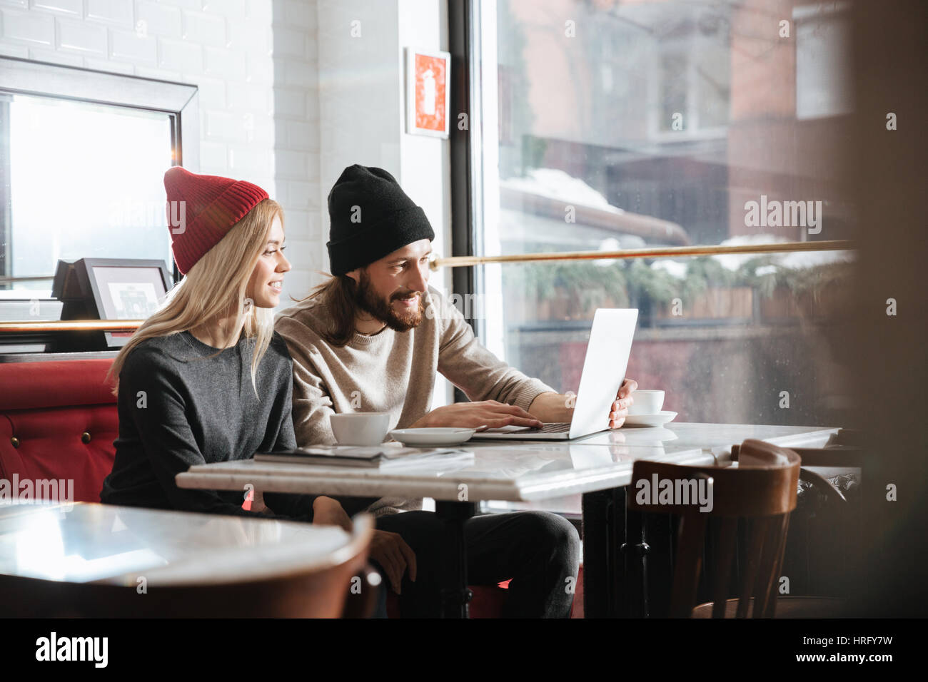 Side view of hipsters with laptop by the table in cafe Stock Photo