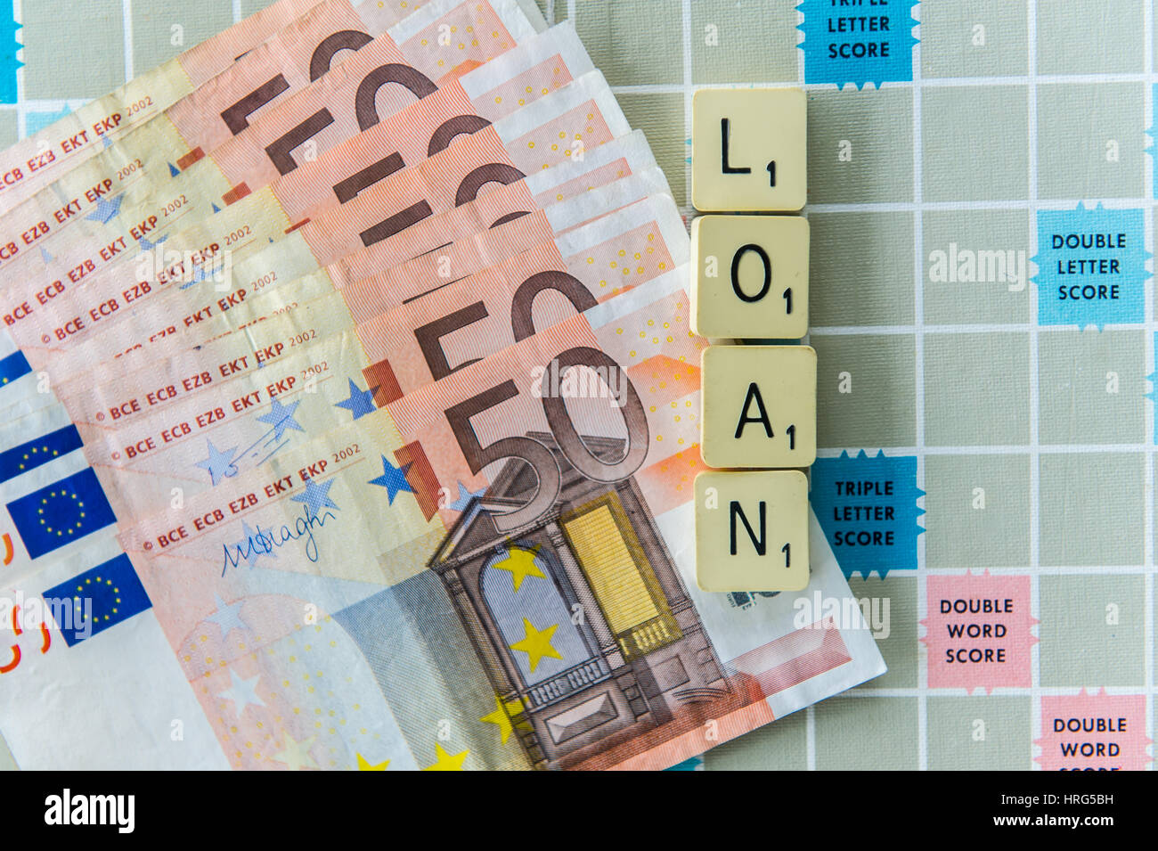 Word 'Loan' spelt out on a Scrabble board with €50 notes as a financial concept with copy space. Stock Photo