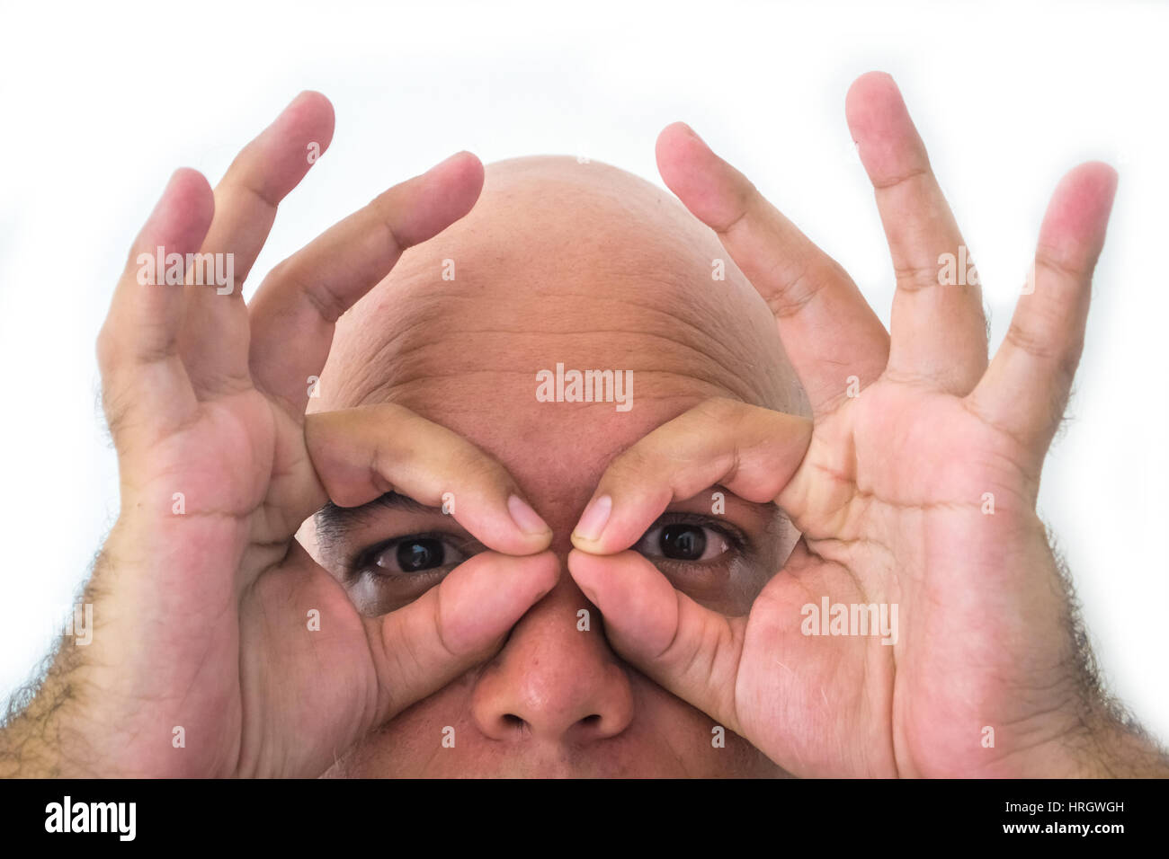 Half face of bald man in white background. Closeup of the eyes. Hands simulating a mask. Stock Photo