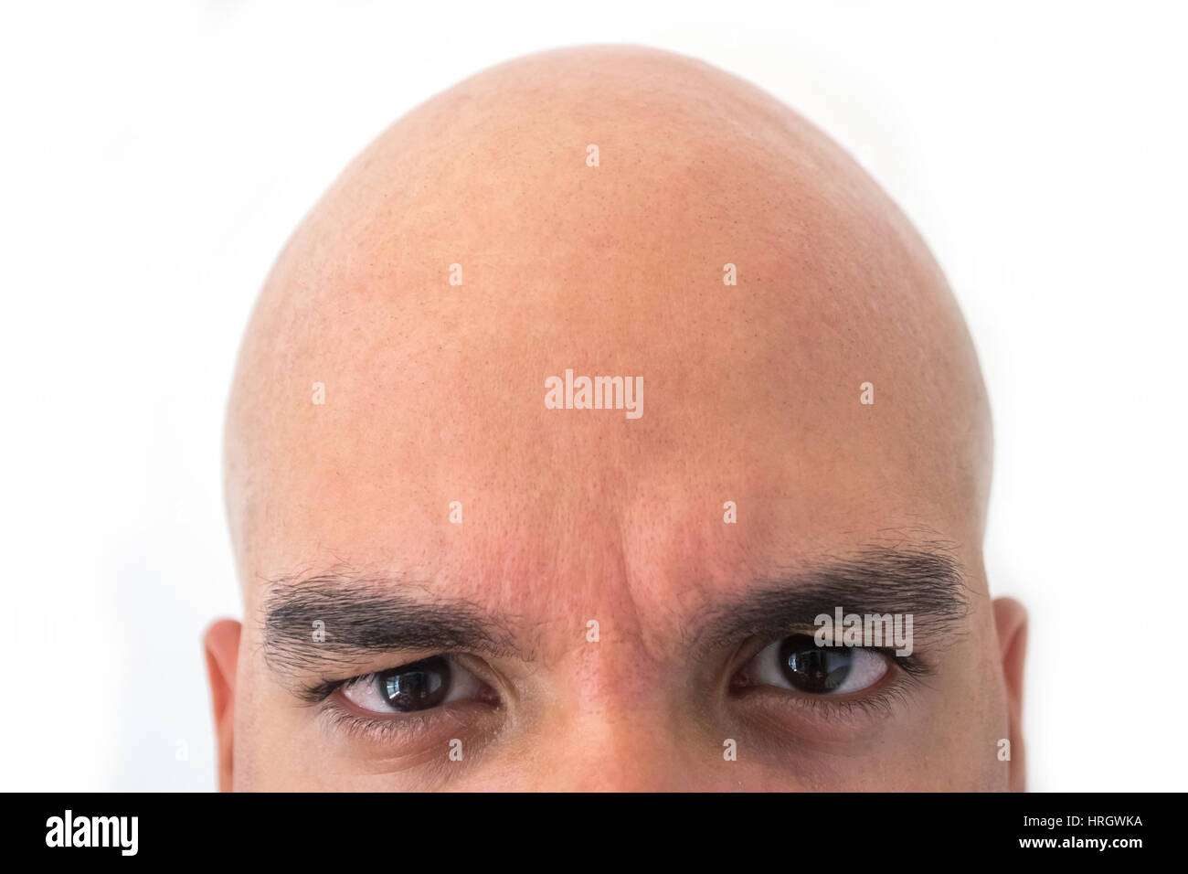 Half face of bald man in white background. Closeup of the eyes. Angry mood. Stock Photo