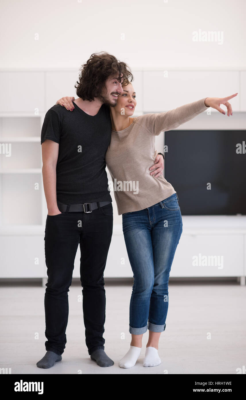 Portrait of a happy young beautiful couple hugging in their new home ...