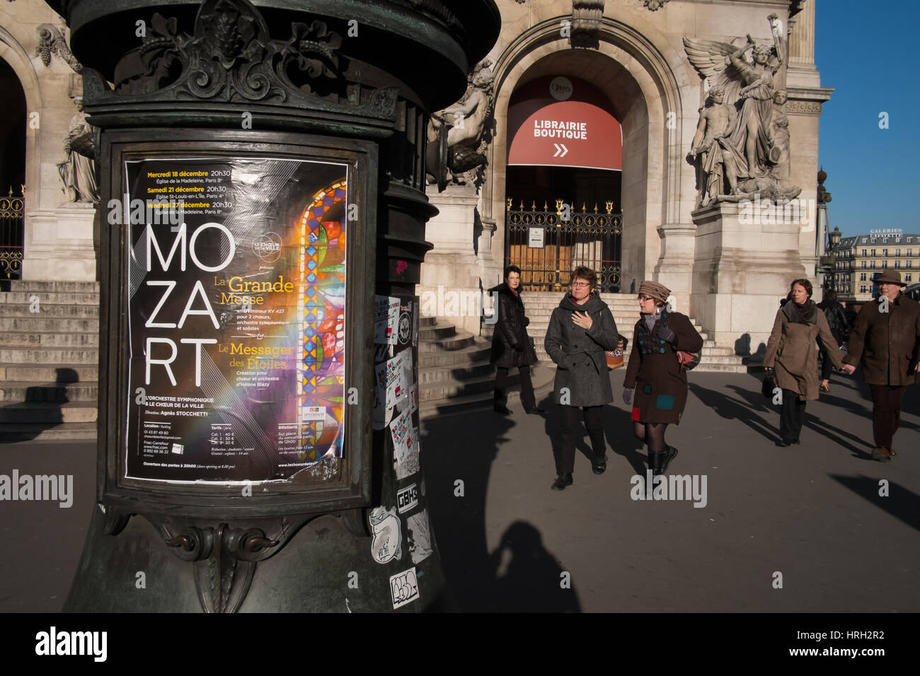 Winter visitors by the Opera Garnier and iconic Paris advertising column. Stock Photo