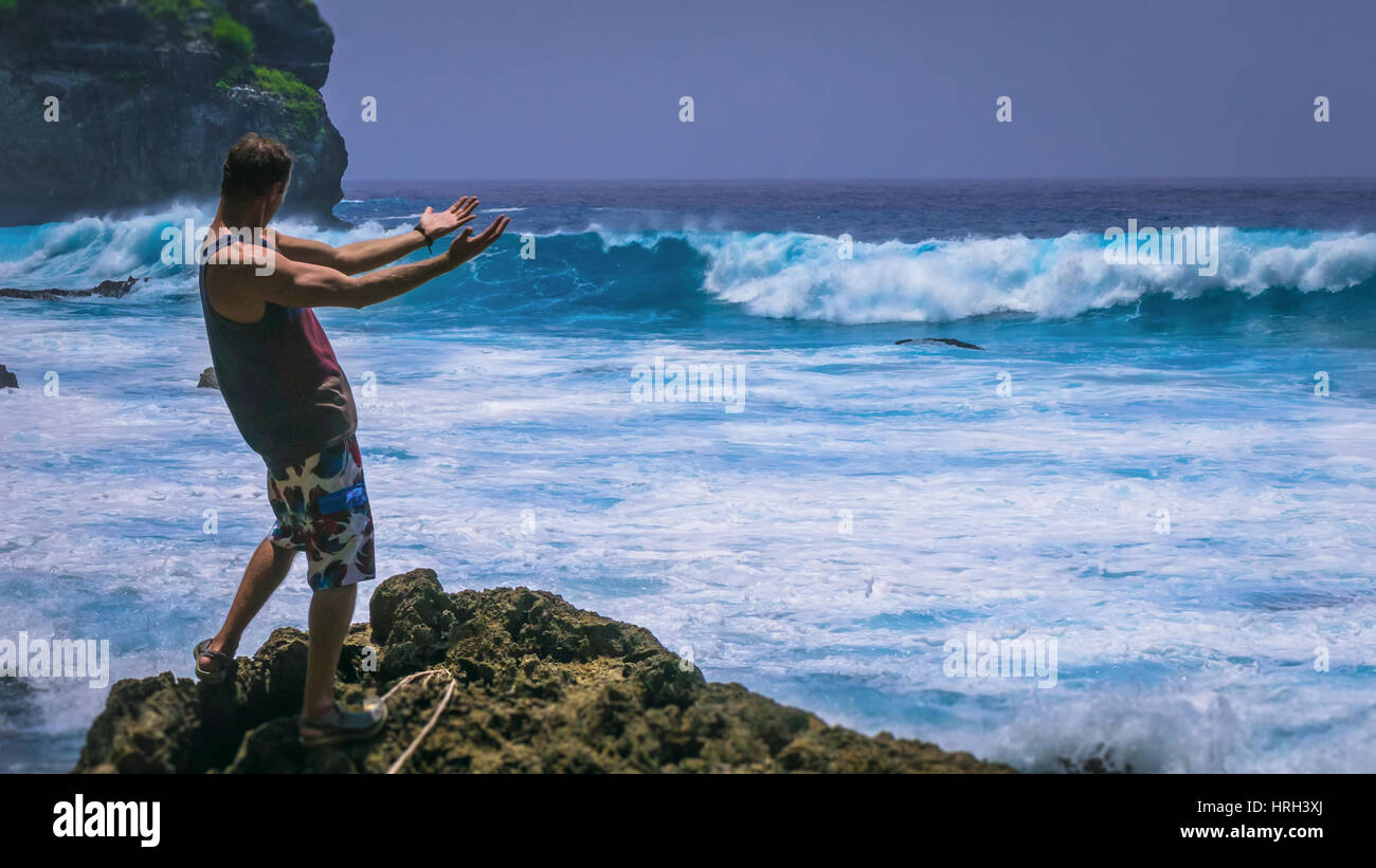 Man Provoke Ocean Waves on Tembeling Coastline at Nusa Penida island, Bali Indonesia Stock Photo