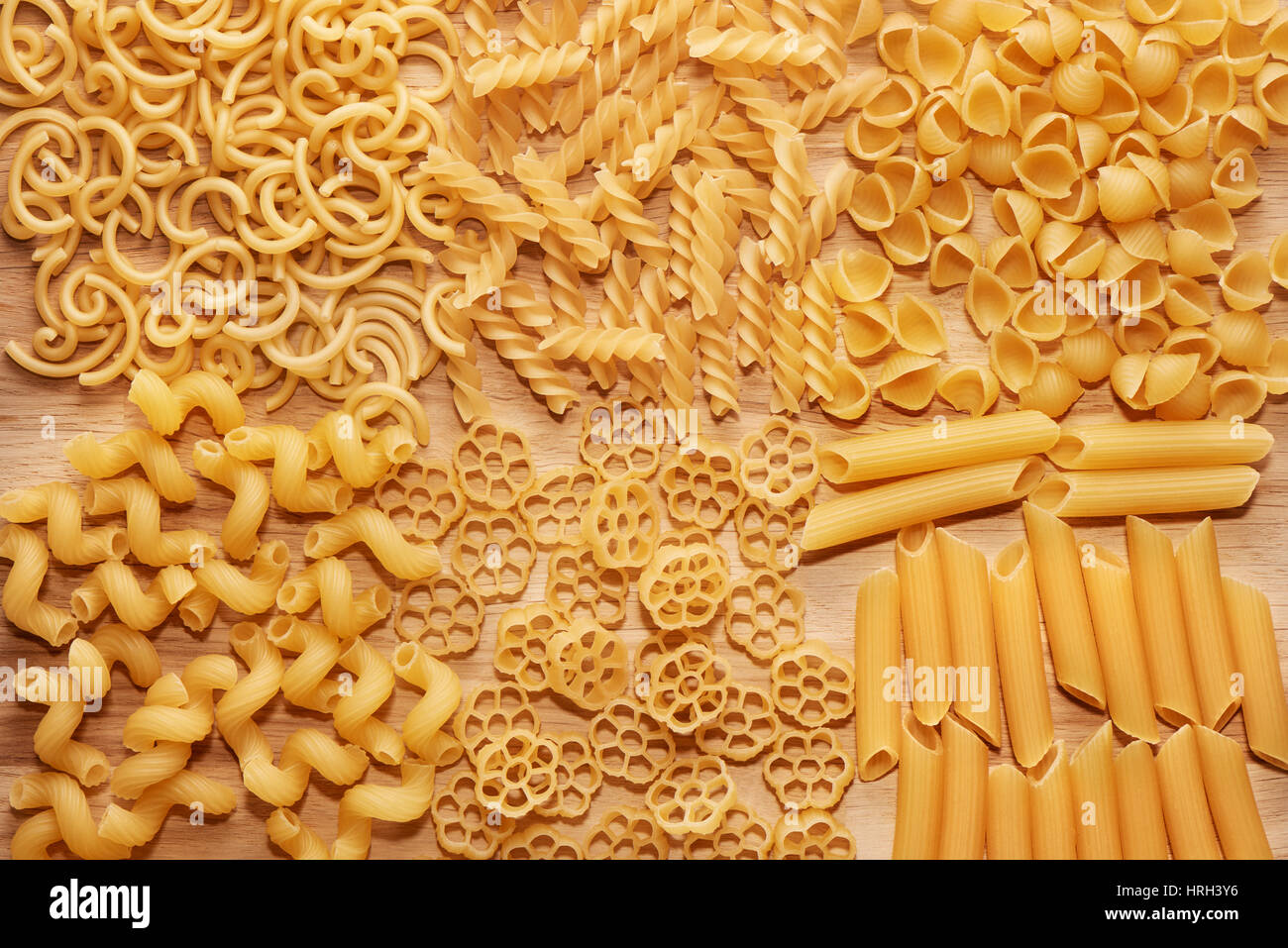 Close up of several types of dry pasta on light wooden table, top view Stock Photo