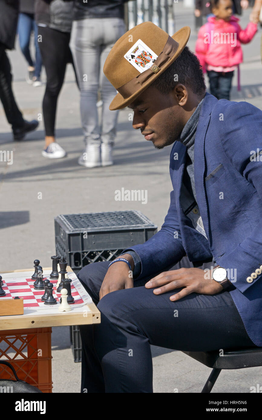A nattily dressed man with an ace of spades card in his hat playing chess at Union Square Park in Manhattan, New York City. Stock Photo