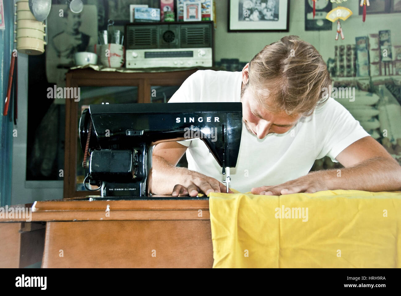 Model released, Junger Mann arbeitet an einer altmodischen Naehmaschine - man working on a vintage sewing machine Stock Photo
