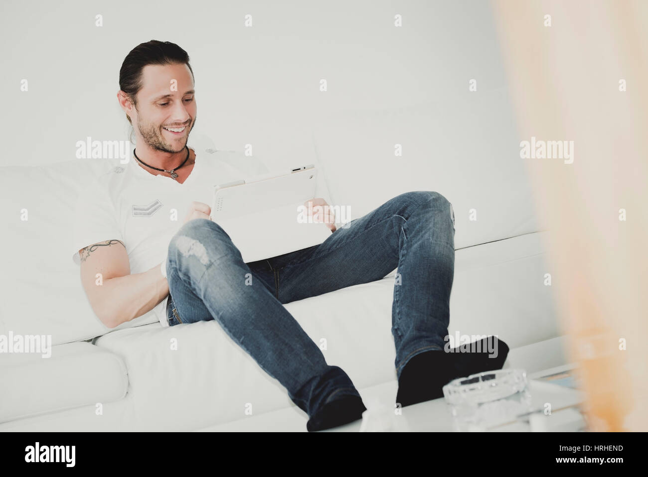 Mann mit IPad auf der Couch - man with Ipad sitting on a couch Stock Photo