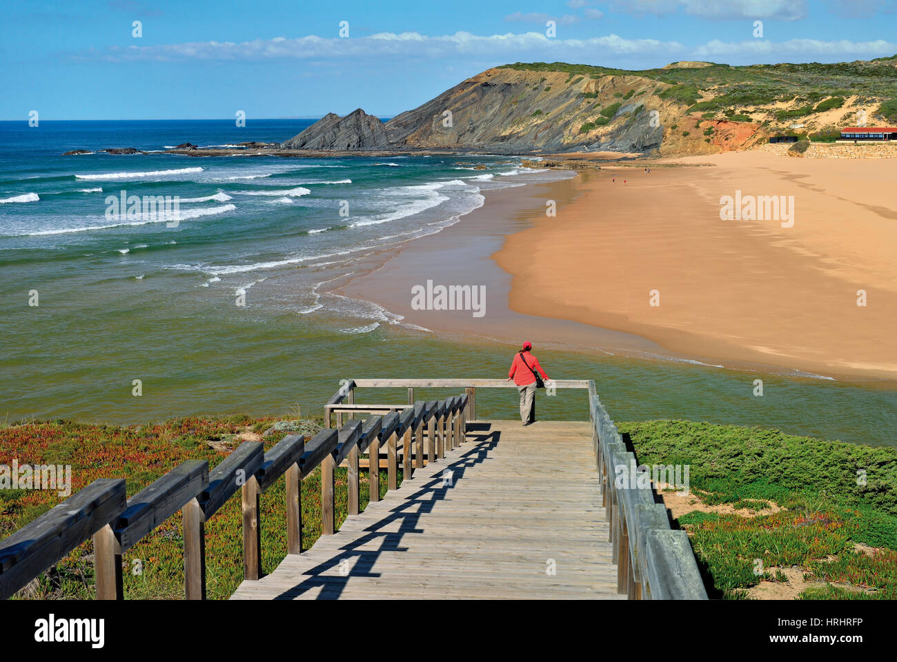 Wooden steps and view point with woman looking to natural beach Stock Photo