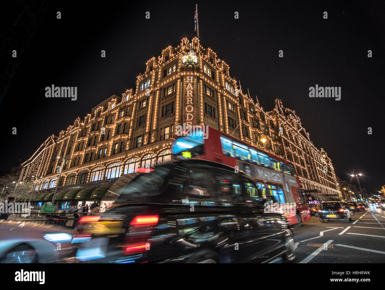 A London taxi and a London bus drive past Harrods, London, England, United Kingdom Stock Photo
