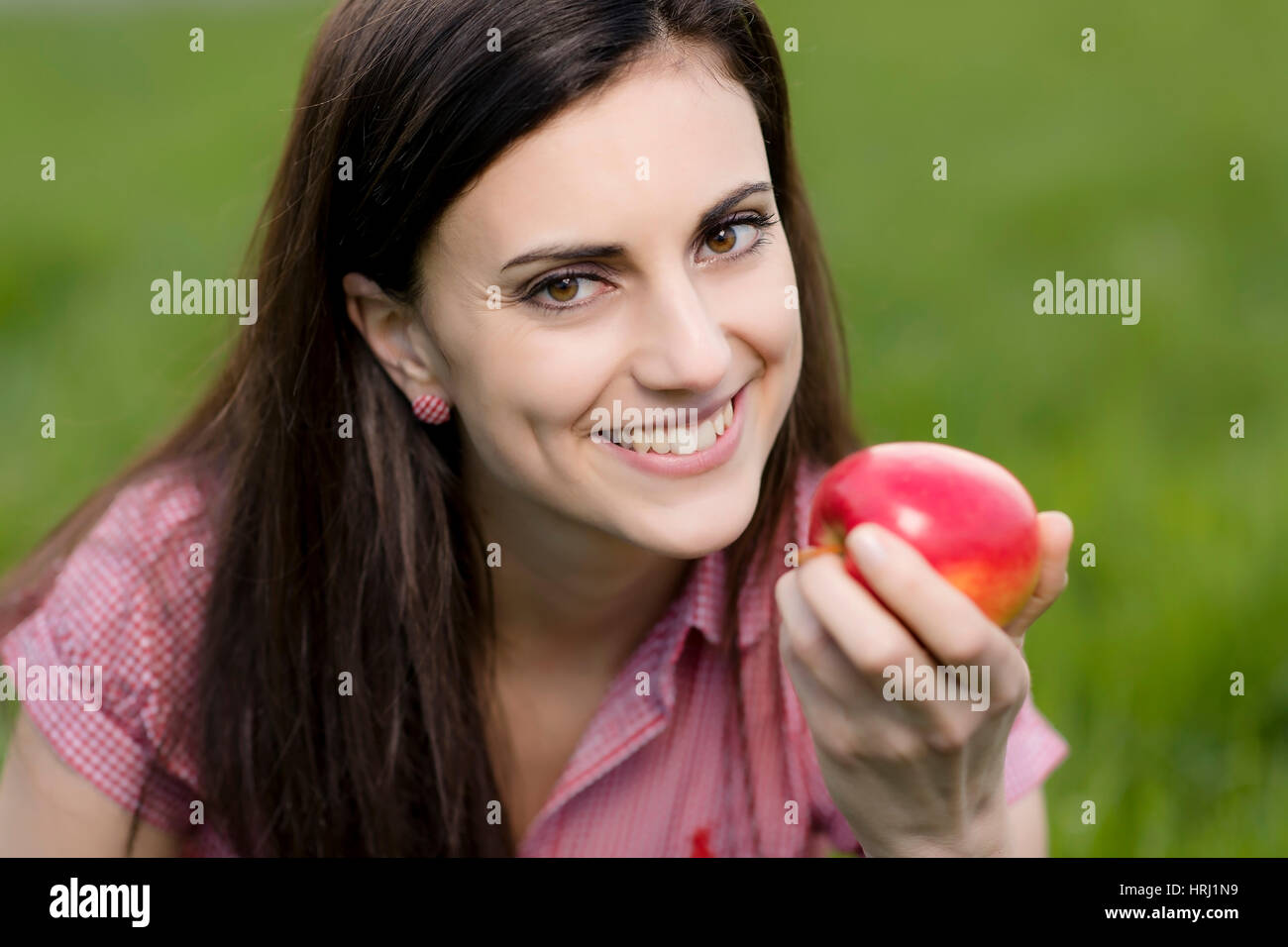 Junge Frau mit Apfel in der Wiese - woman with apple in meadow Stock Photo
