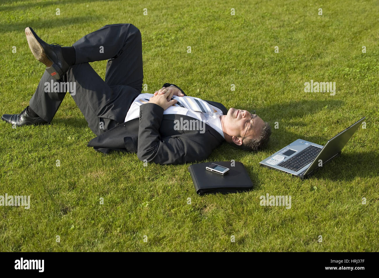 Businessman rests in the meadow - businessman relaxing in meadow Stock Photo