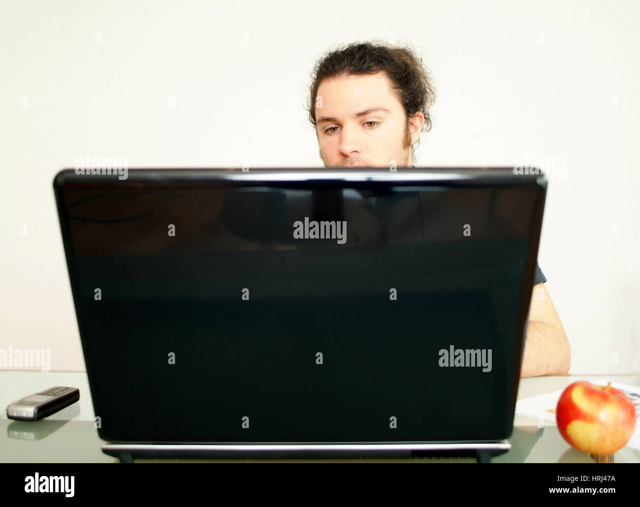 Mann arbeitet am Notebook, daneben liegt ein Apfel - man using laptop, aside an apple Stock Photo