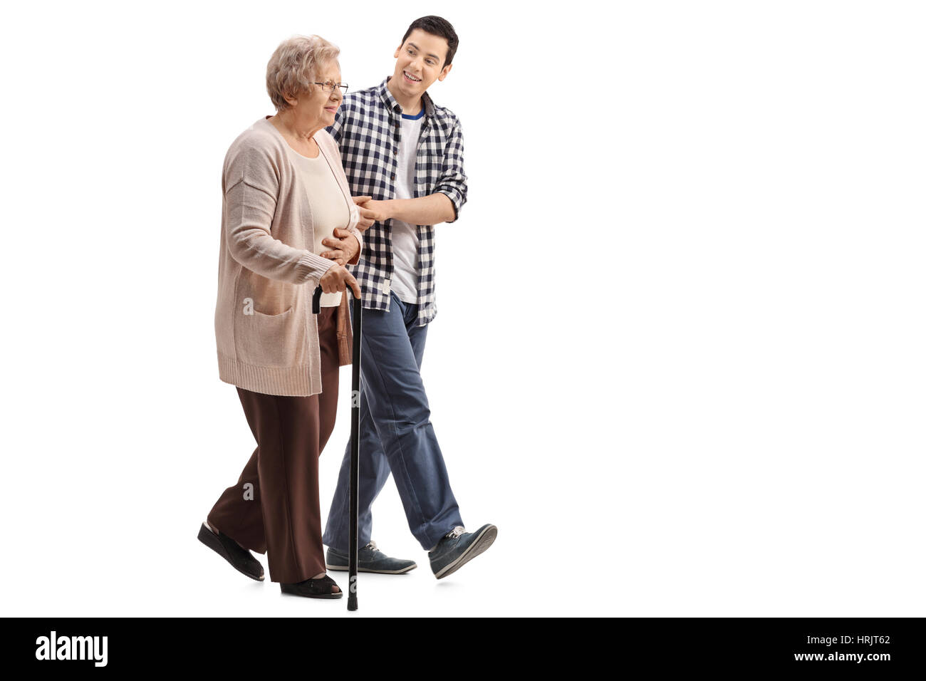 Full length profile shot of an elderly woman with a walking cane walking with a young man isolated on white background Stock Photo