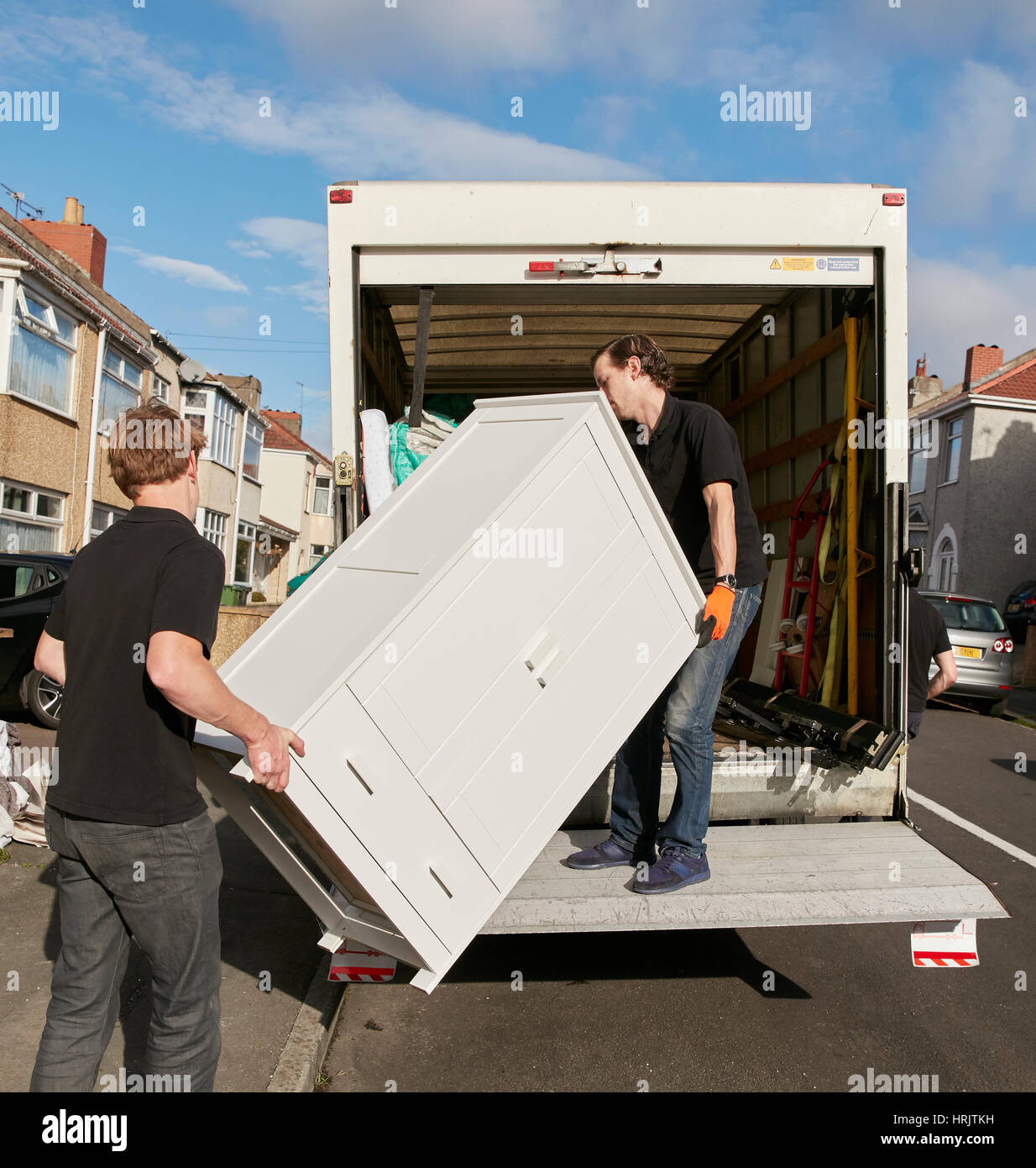 Removals business. Two men lifting a wardrobe onto the removals van. Stock Photo