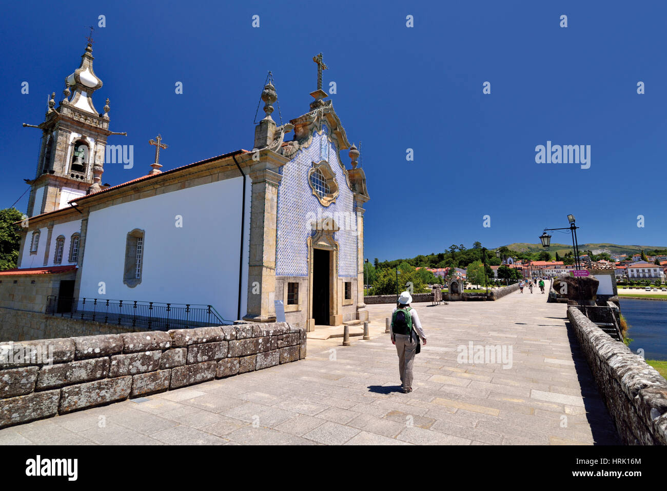 Portugal: Woman with backpack walking along roman bridge and medieval chapel in St. James Way stop Ponte de Lima Stock Photo