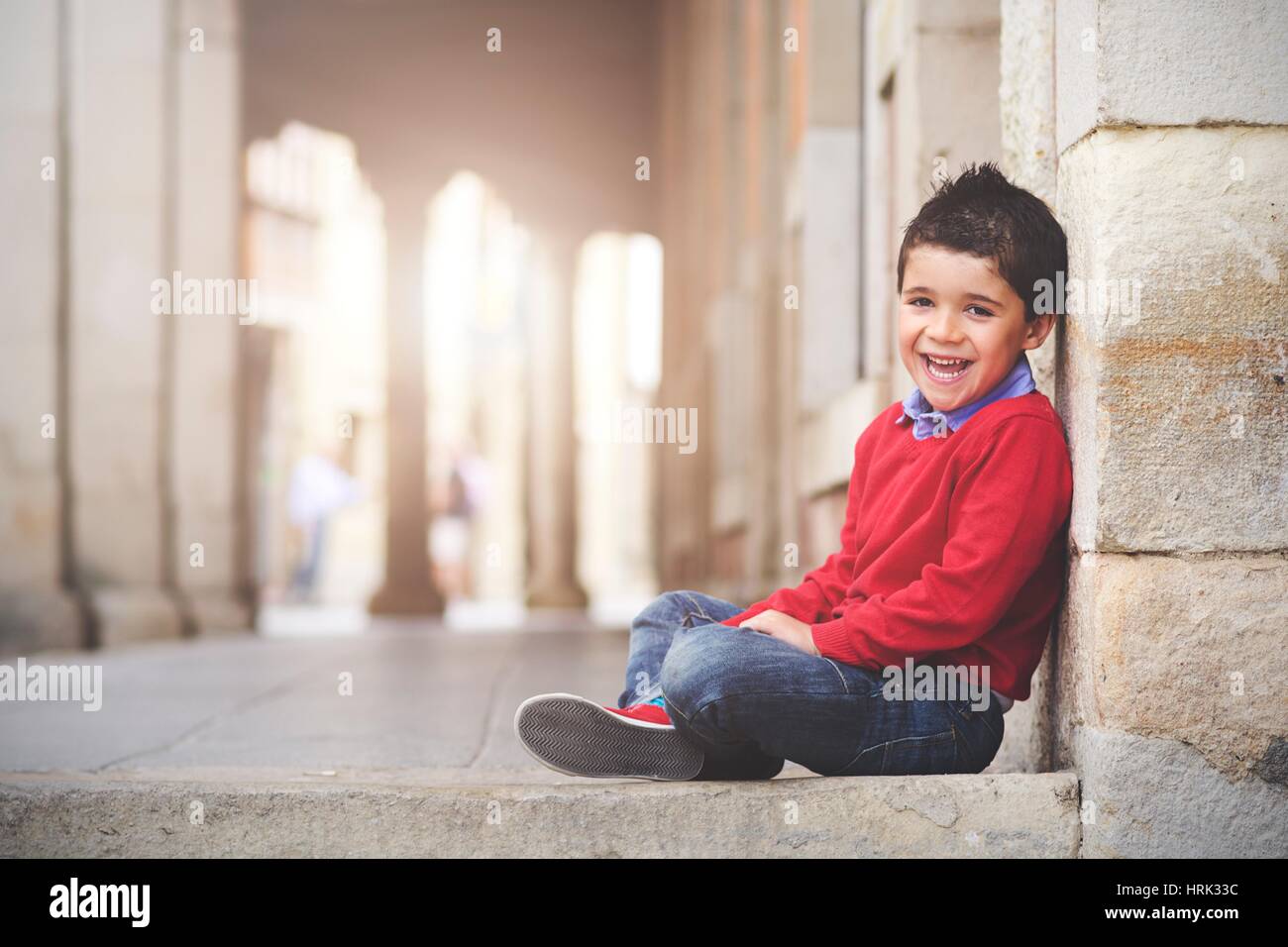 Happy and smiling boy sitting on the floor Stock Photo - Alamy