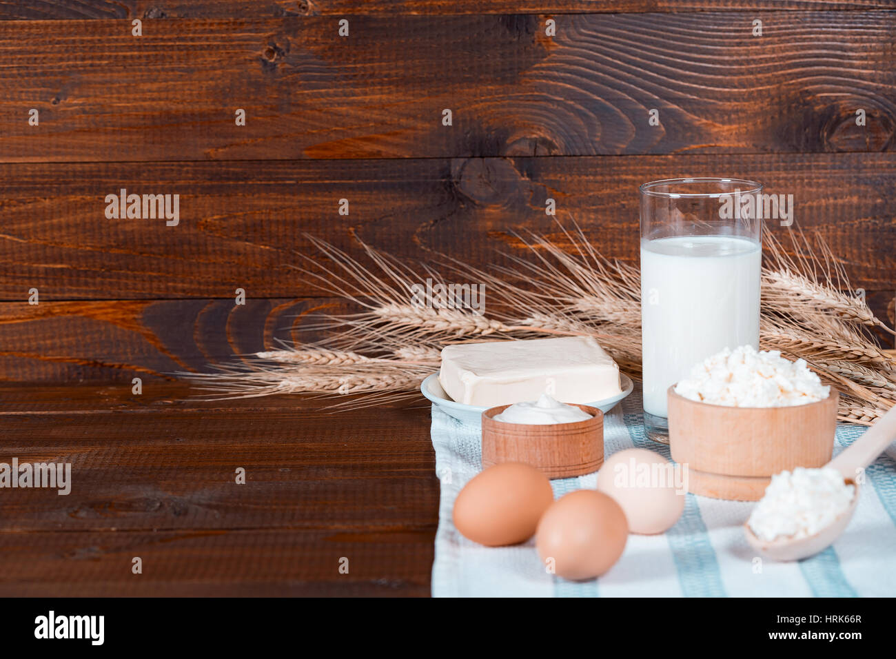 Natural homemade products: milk, cheese, sour cream and eggs on old wooden background with ears of wheat. With space for your text Stock Photo