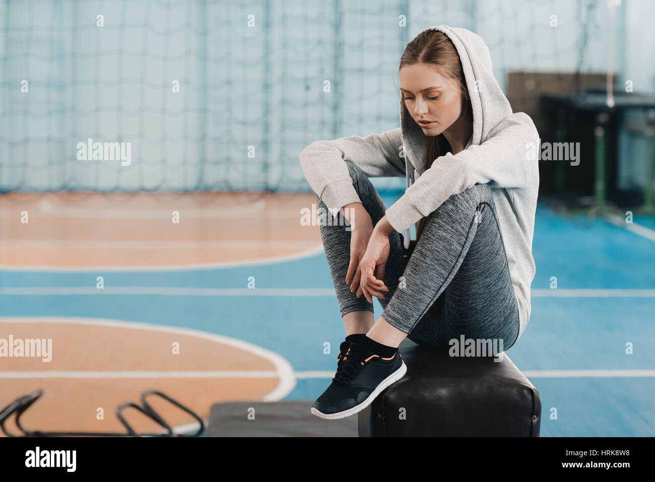 Young sporty woman sitting on pommel horse and looking down Stock Photo