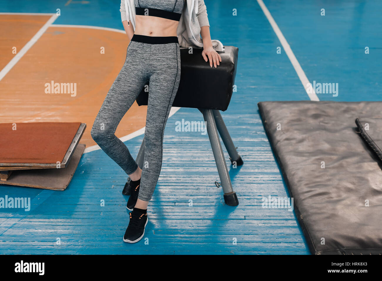 Partial view of young sportswoman leaning at pommel horse in gym Stock Photo
