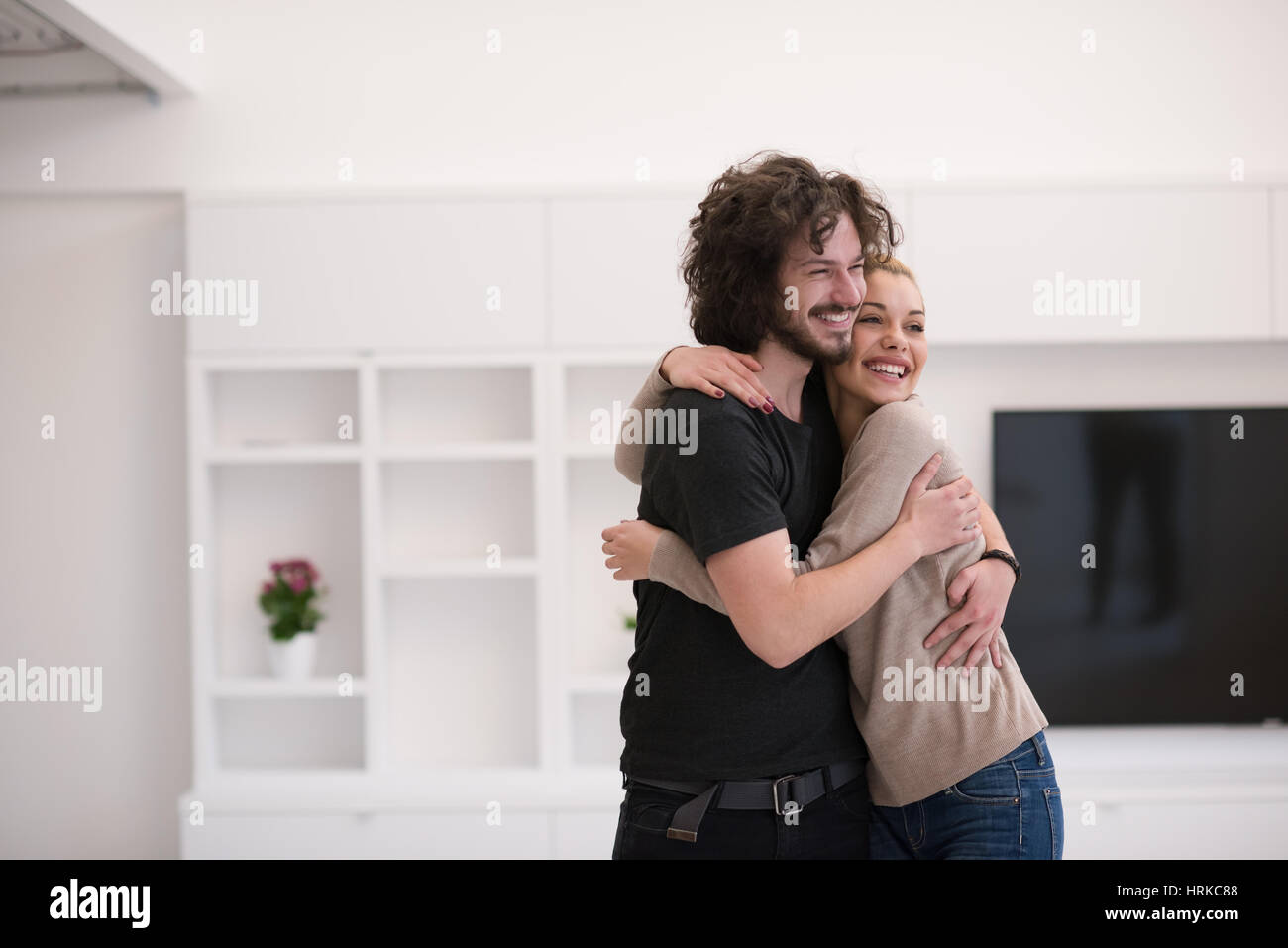 Portrait of a happy young beautiful couple hugging in their new home ...