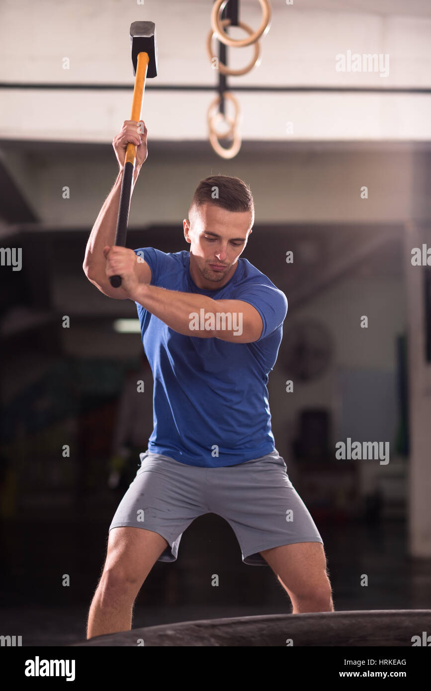 Sledgehammer Tire Hits young muscular man workout at gym with hammer