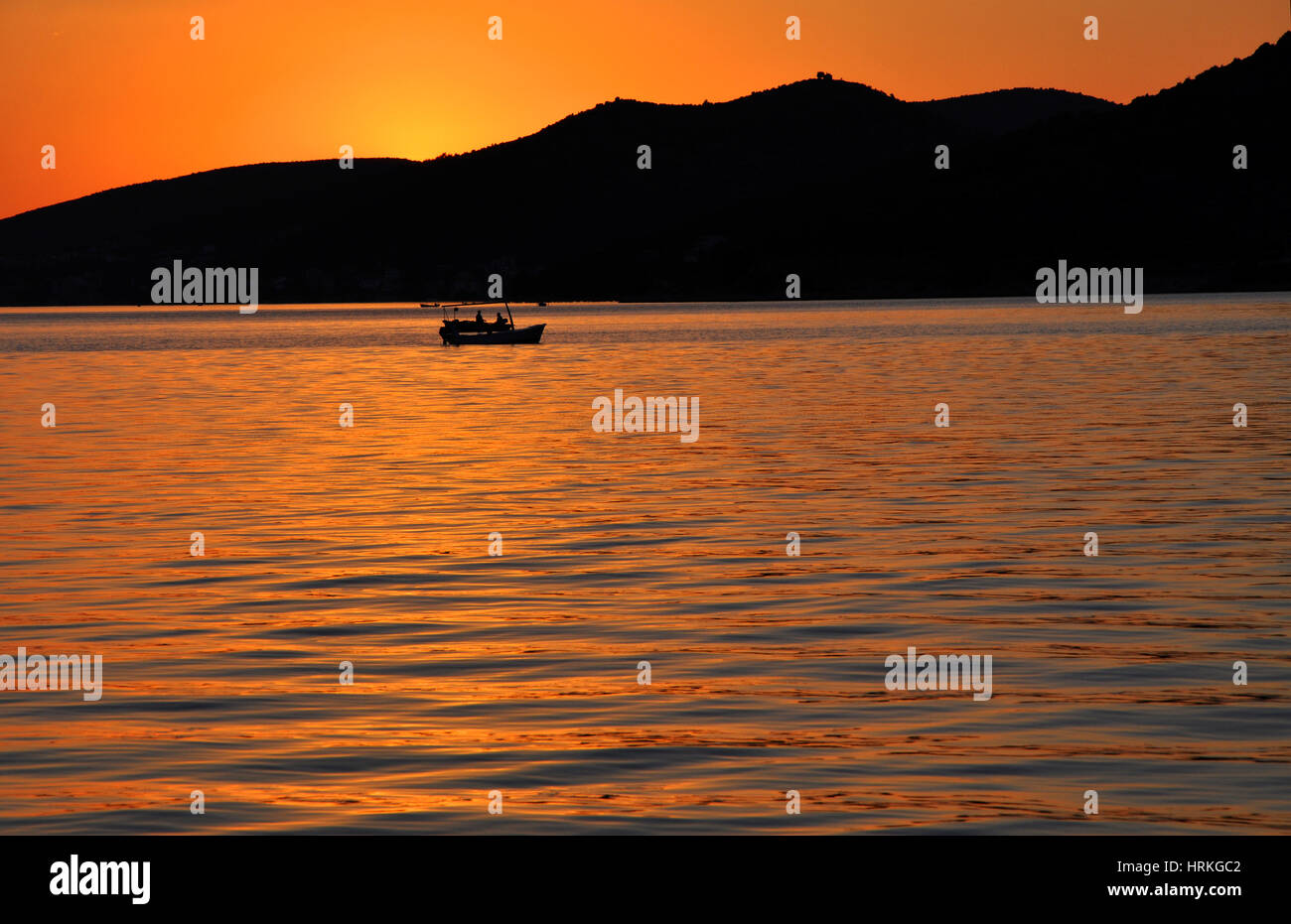 Romantic sunset on the sea with a fishing boat Stock Photo - Alamy