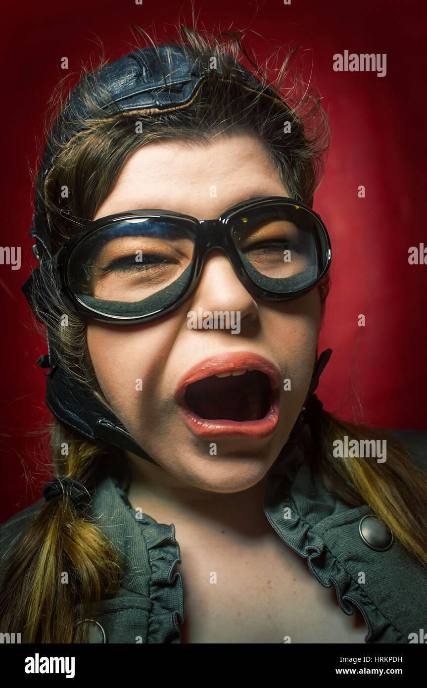 Girl wearing aviator hat and goggles makes silly facial expression from ...