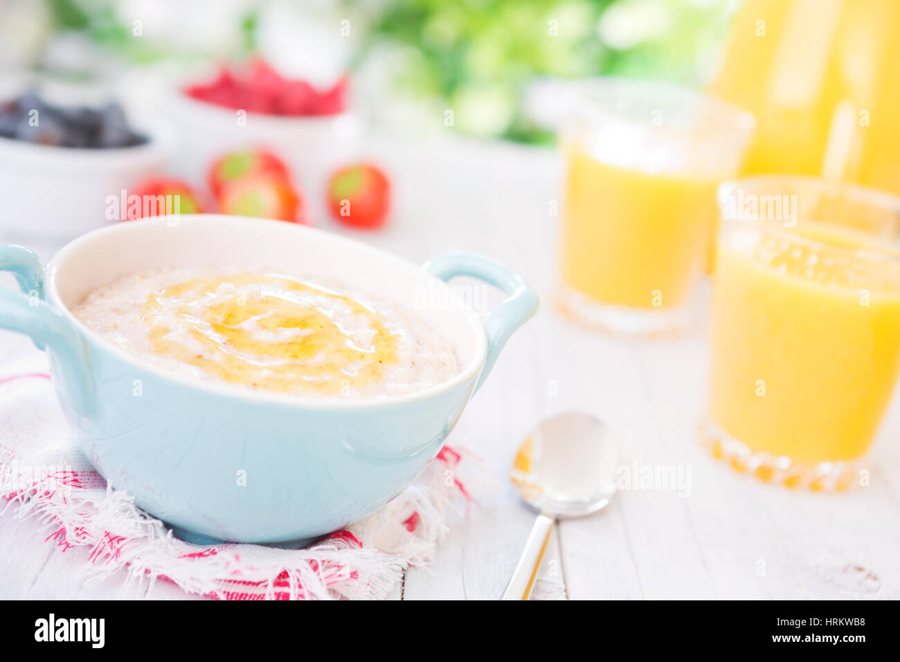 A bowl with homemade oatmeal porridge with honey on a rustic outdoor table. Stock Photo