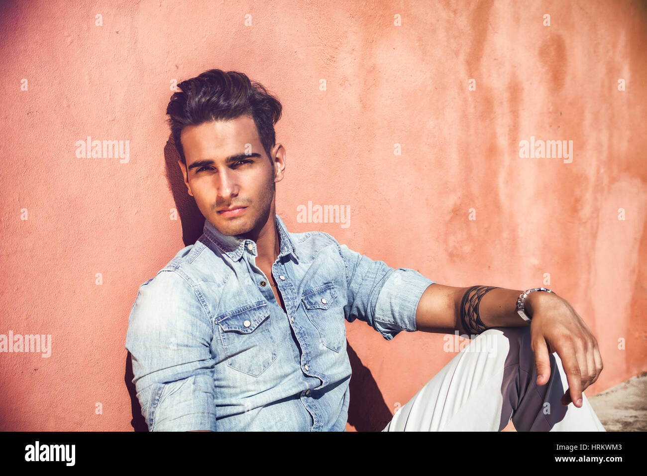 Handsome man sitting on stairs while looking away Stock Photo - Alamy