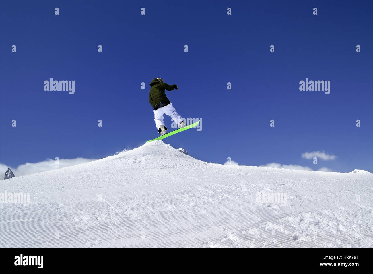 Snowboarder jump in snow park at ski resort on sun winter day. Caucasus Mountains, region Dombay. Stock Photo