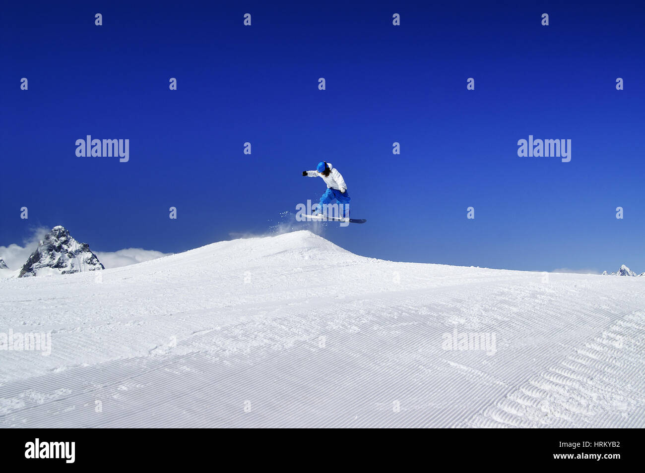 Snowboarder jump in snow park at ski resort on sunny winter day. Caucasus Mountains, region Dombay. Stock Photo