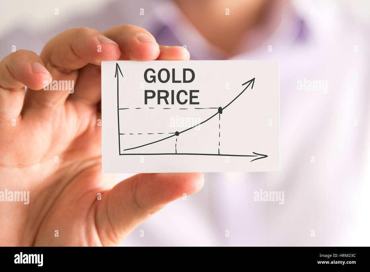 Closeup on businessman holding a card with GOLD PRICE rising arrow and ...