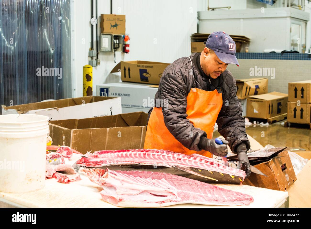 New York City, USA. Wholesale market stall employee cutting up fresh