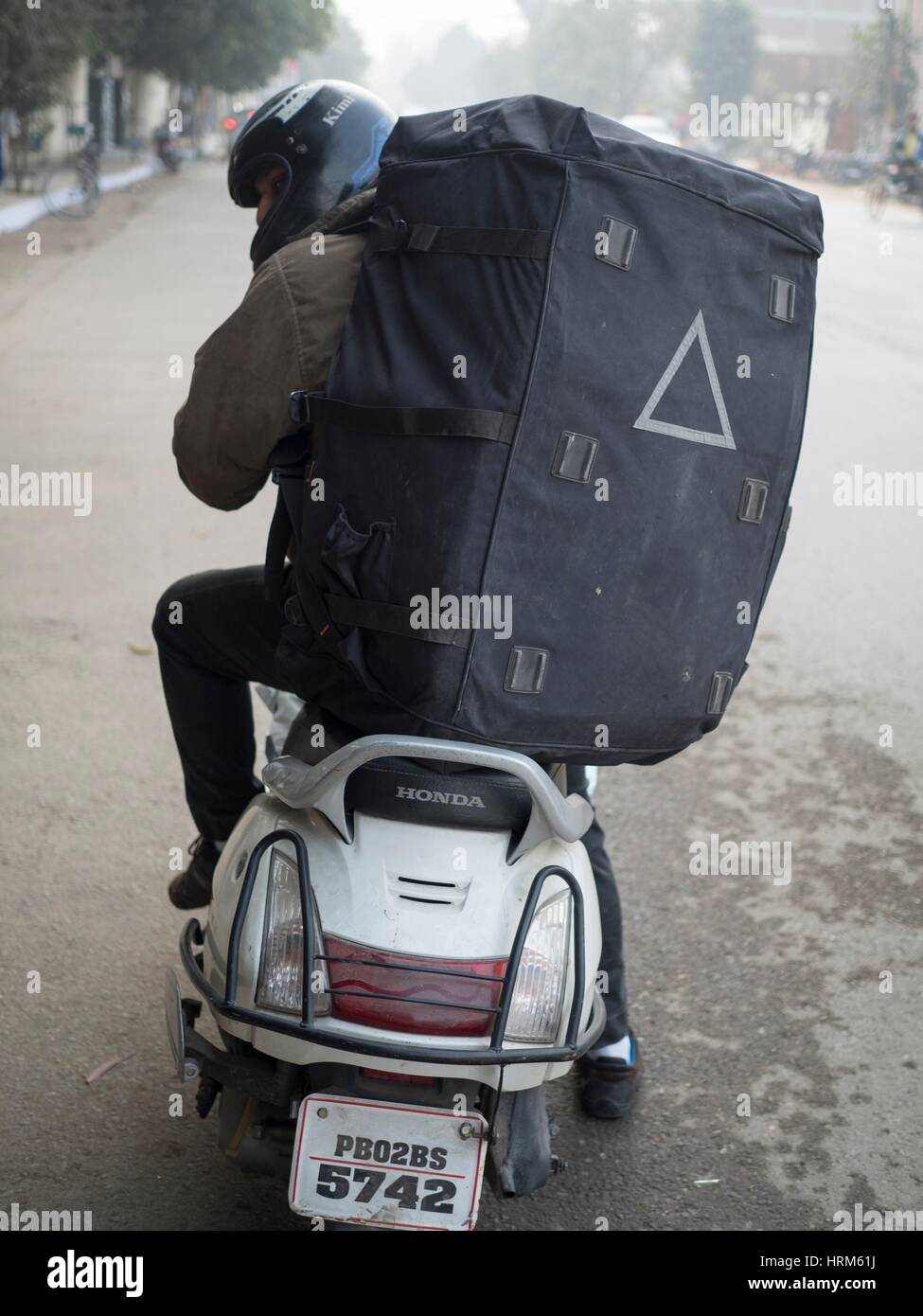 Man carrying luggage on scooter in Amritsar, Punjab, India Stock Photo