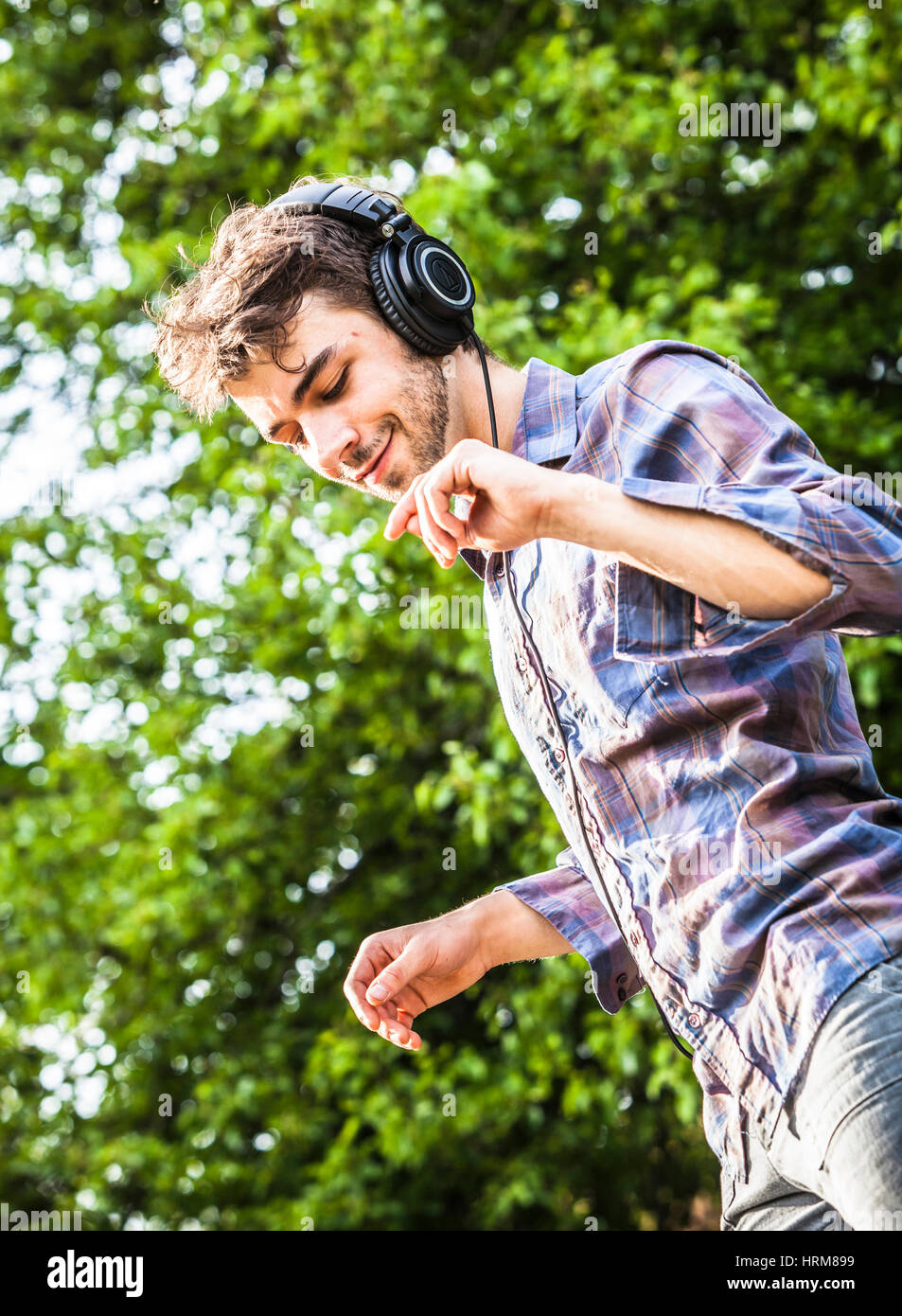 A young man listening to music on headphones and dancing. Stock Photo