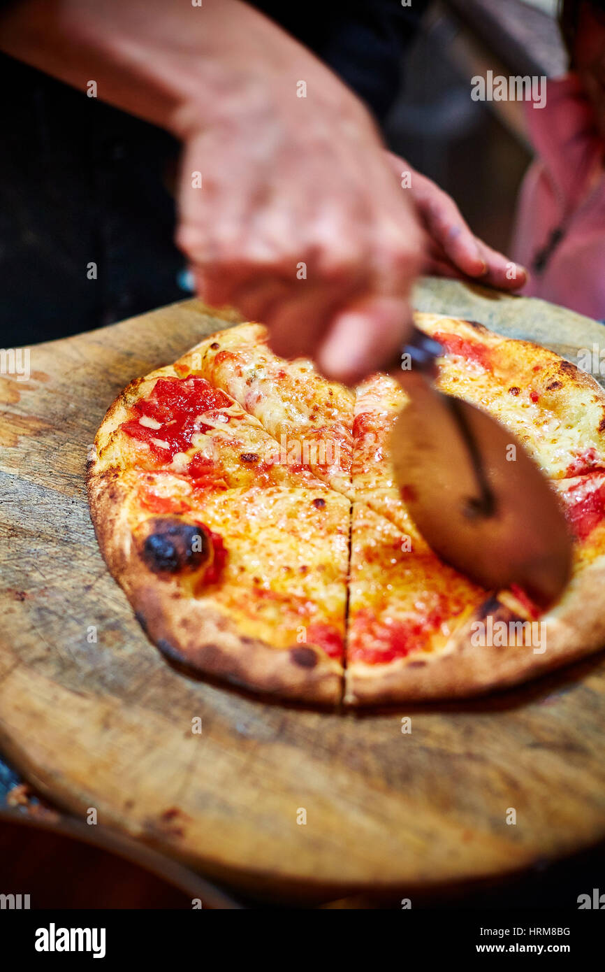 wood fired stone baked pizza being cut Stock Photo Alamy