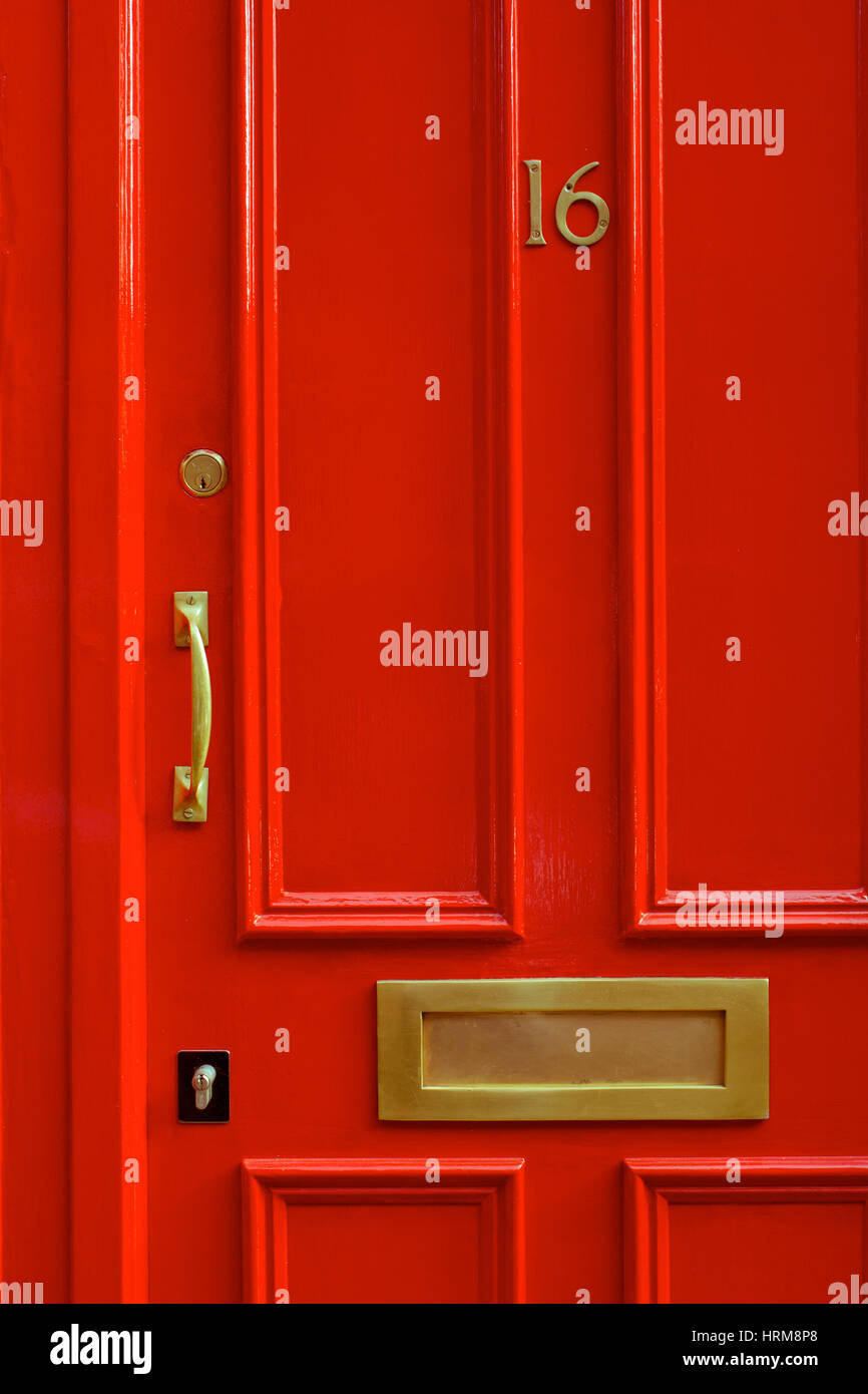A detail close-up shot of a bight red entry door with a brass handle and letter slot in Covent Garden,  London, England Stock Photo