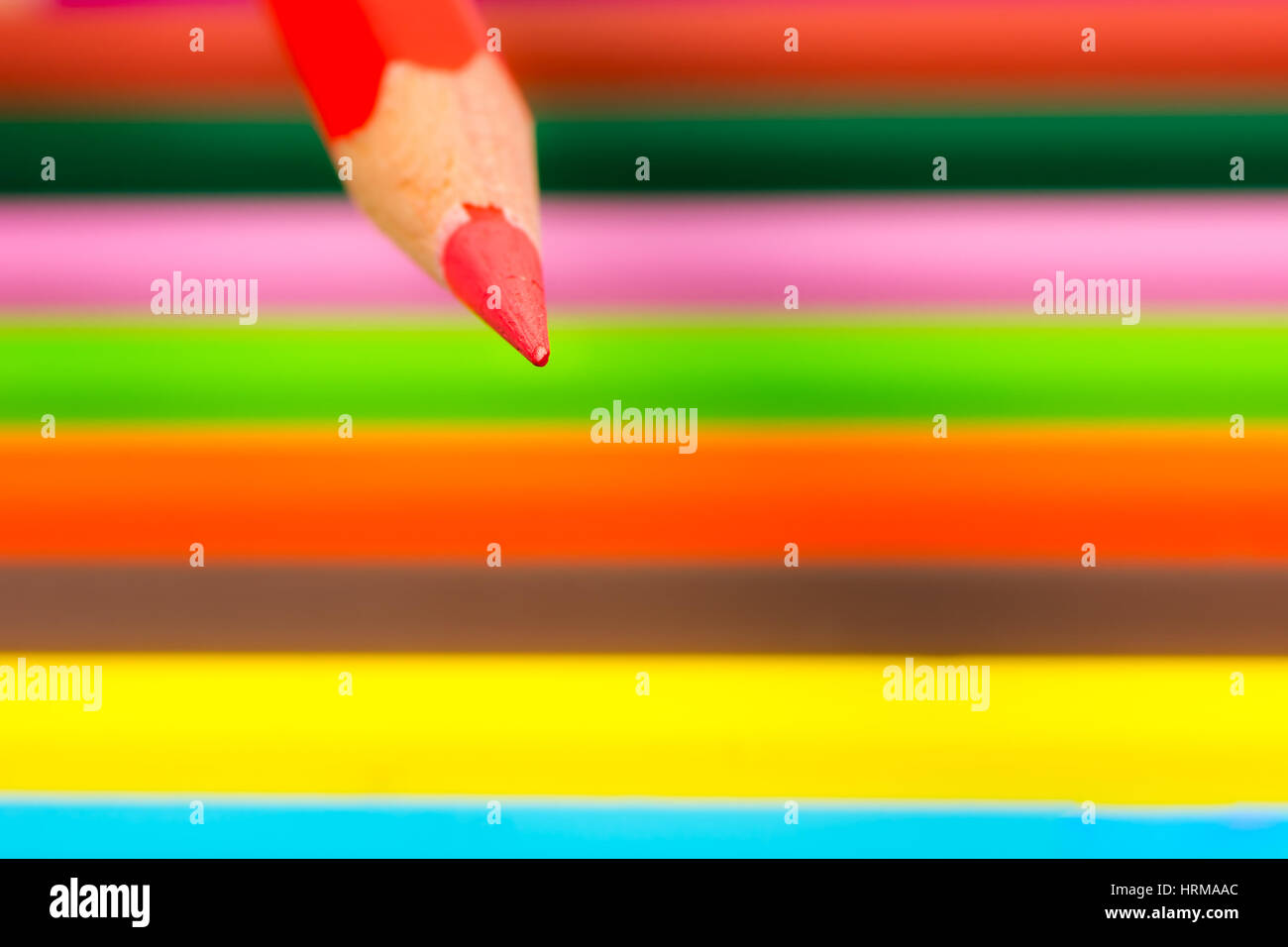 Tip of a red wooden pencil with colored crayons in the background  - selective focus Stock Photo